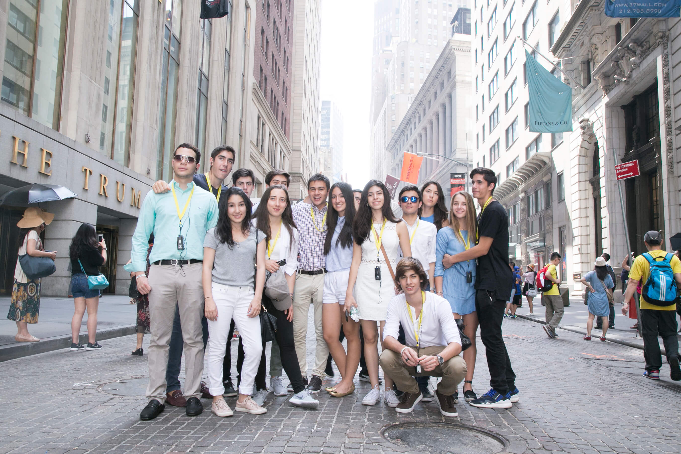 Visionarium students walking together down a narrow street in Lower Manhattan, tall buildings on both sides.