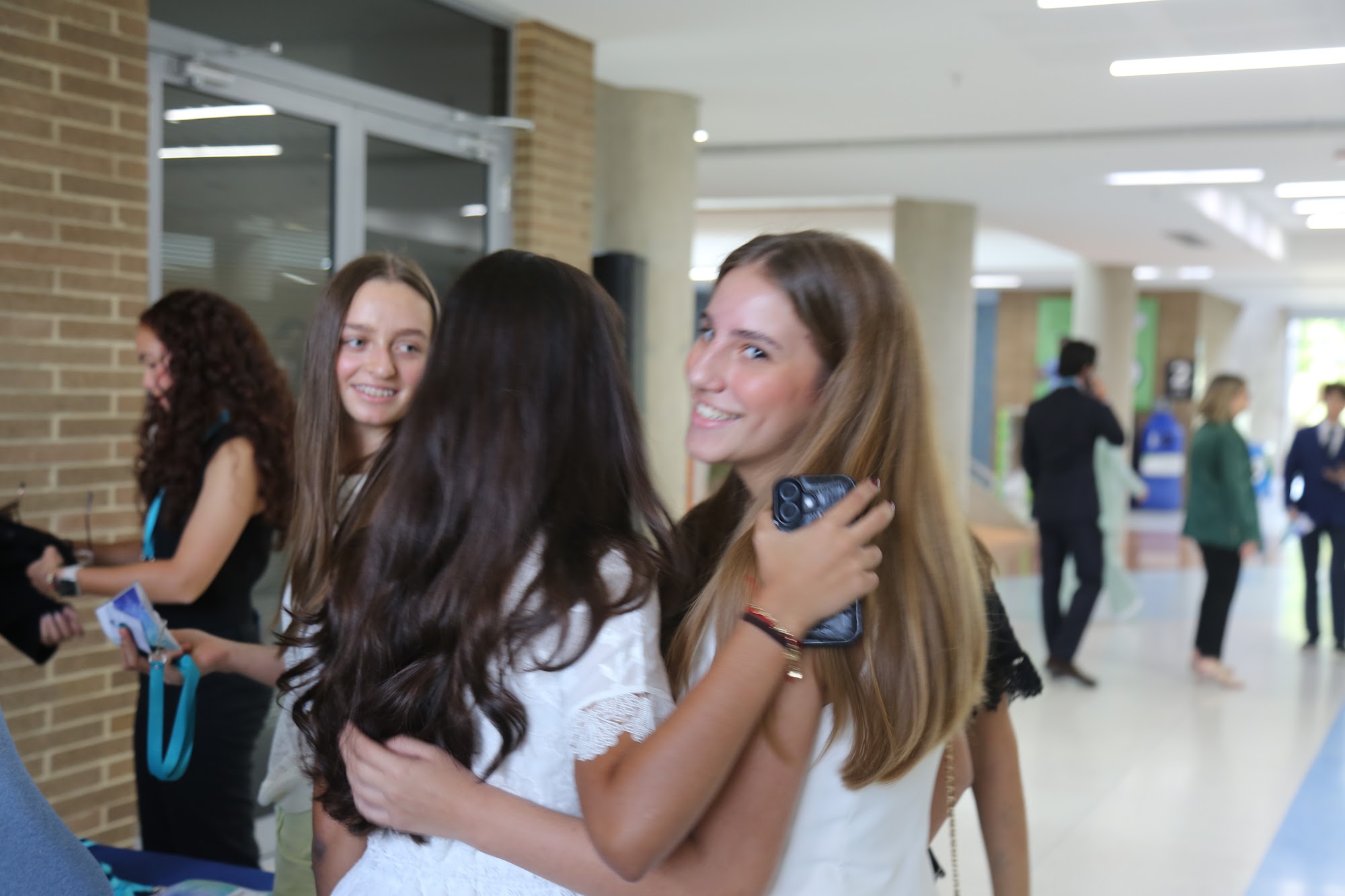 Three students greeting each other in the corridor before the day begins.