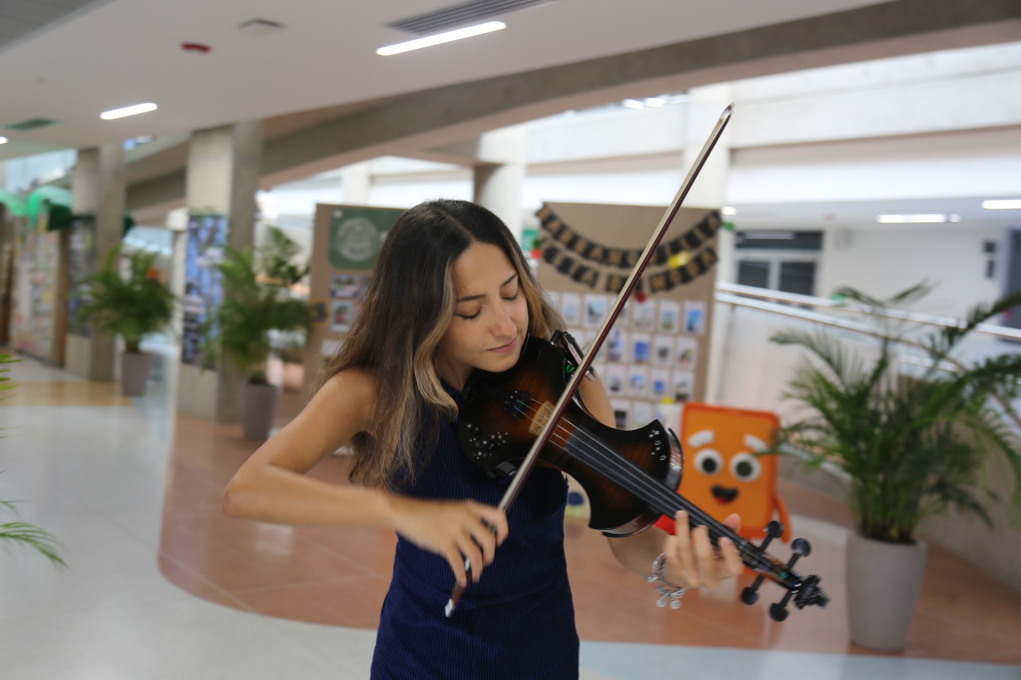 A student plays the violin in the library as the group gathers.