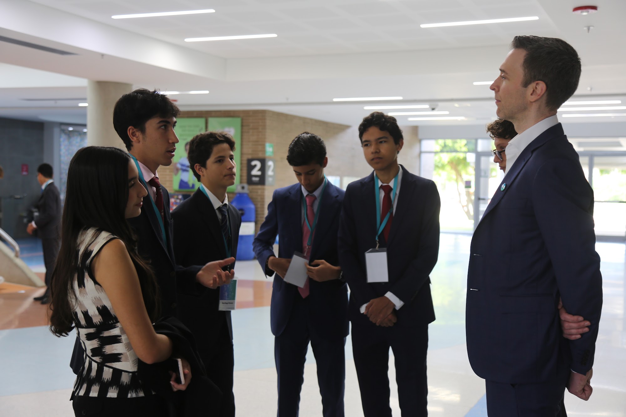Students standing in a circle with a mentor in the corridor.